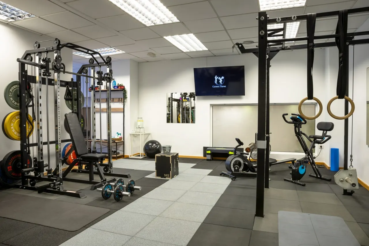Sala de entrenamiento con rack, banco y máquina de remo